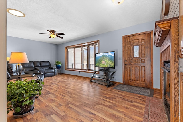 living room with ceiling fan, wood-type flooring, and a textured ceiling