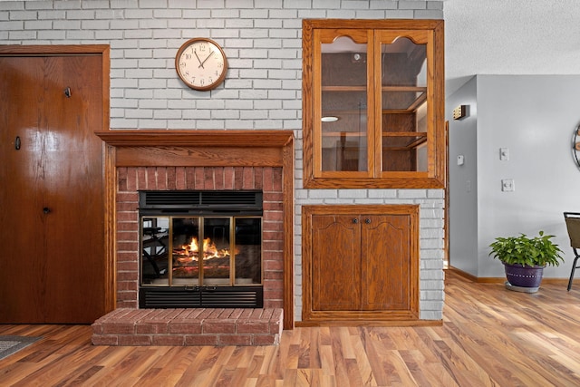 room details featuring hardwood / wood-style floors, a brick fireplace, and a textured ceiling