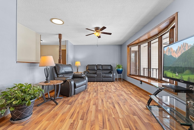 living room featuring ceiling fan, light hardwood / wood-style flooring, and a textured ceiling