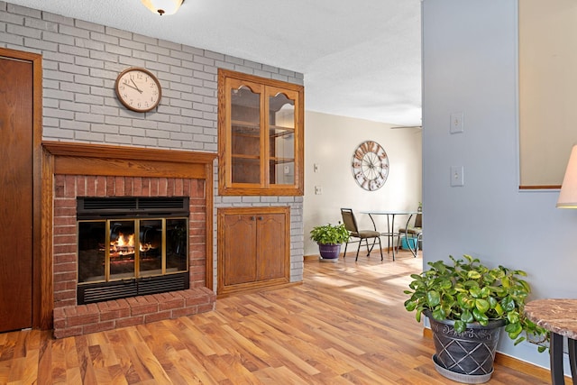 living room with a textured ceiling, a fireplace, and light hardwood / wood-style flooring