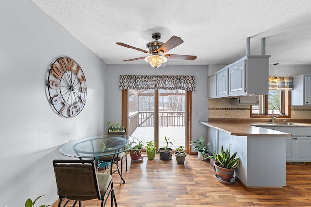 kitchen with sink, wood-type flooring, kitchen peninsula, and a healthy amount of sunlight