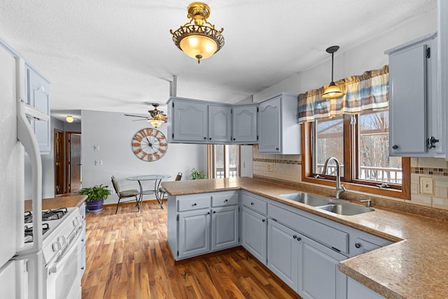 kitchen with sink, white appliances, tasteful backsplash, dark hardwood / wood-style flooring, and kitchen peninsula