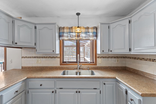 kitchen featuring white cabinetry, decorative light fixtures, and sink