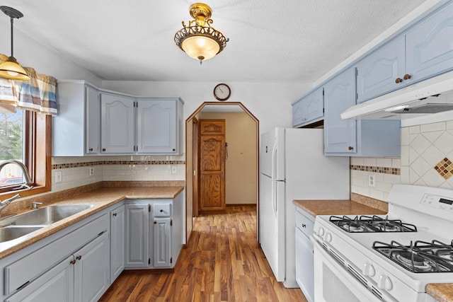 kitchen featuring sink, white gas stove, hanging light fixtures, dark hardwood / wood-style flooring, and backsplash