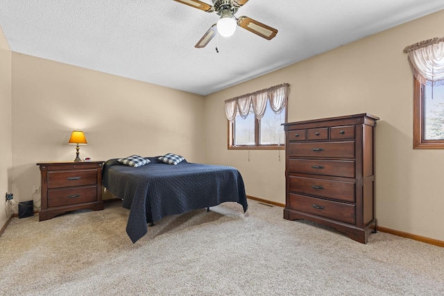 bedroom with ceiling fan, light carpet, and a textured ceiling