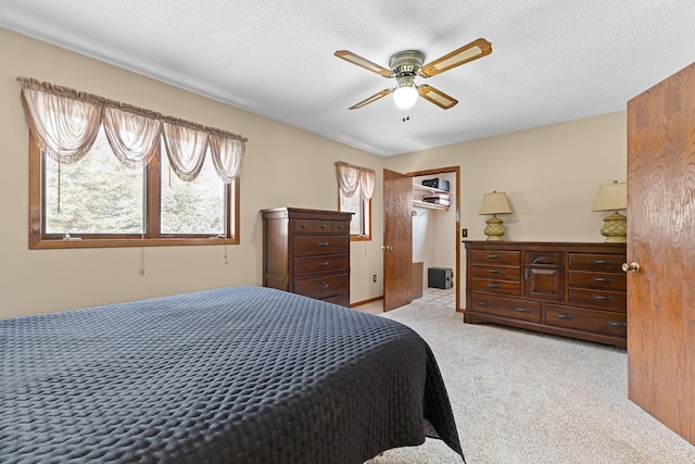 bedroom featuring light carpet, ceiling fan, and a textured ceiling