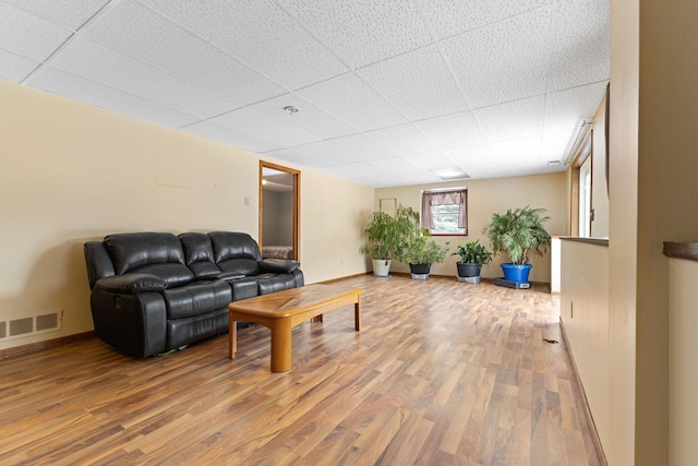 living room with hardwood / wood-style flooring and a paneled ceiling