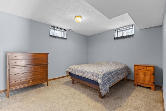 bedroom featuring multiple windows, light carpet, and a textured ceiling