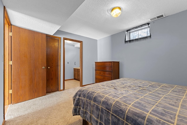 carpeted bedroom with a closet and a textured ceiling