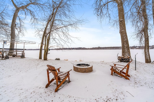 yard covered in snow featuring a water view and an outdoor fire pit