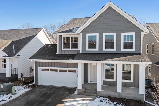 view of front of home featuring central AC unit, a garage, and covered porch