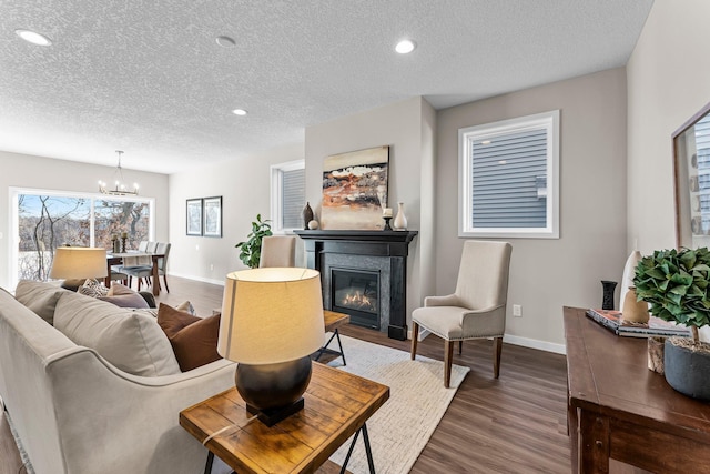 living room with an inviting chandelier, dark wood-type flooring, and a textured ceiling