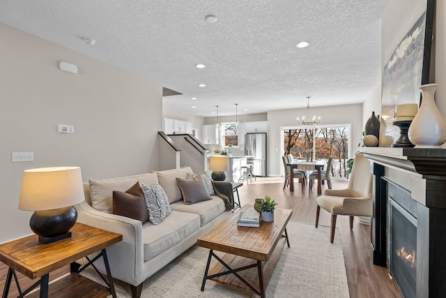 living room with a notable chandelier, light hardwood / wood-style flooring, and a textured ceiling