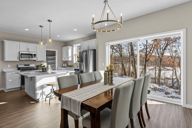 dining space featuring dark hardwood / wood-style flooring, a textured ceiling, and an inviting chandelier