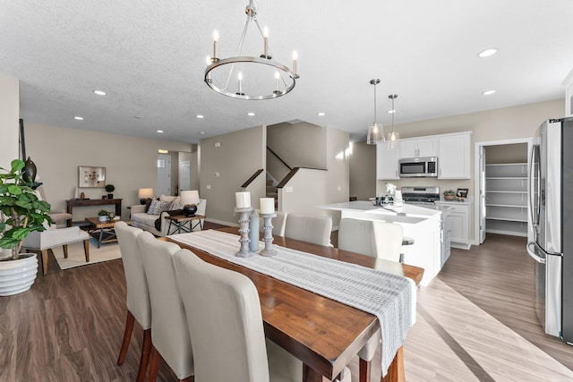 dining space featuring hardwood / wood-style flooring, an inviting chandelier, and a textured ceiling