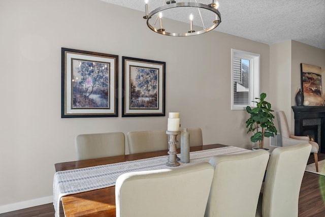 dining area with a notable chandelier, dark wood-type flooring, and a textured ceiling