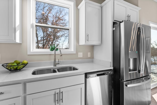 kitchen with appliances with stainless steel finishes, light stone countertops, sink, and white cabinets