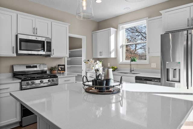 kitchen with white cabinetry, sink, hanging light fixtures, and appliances with stainless steel finishes