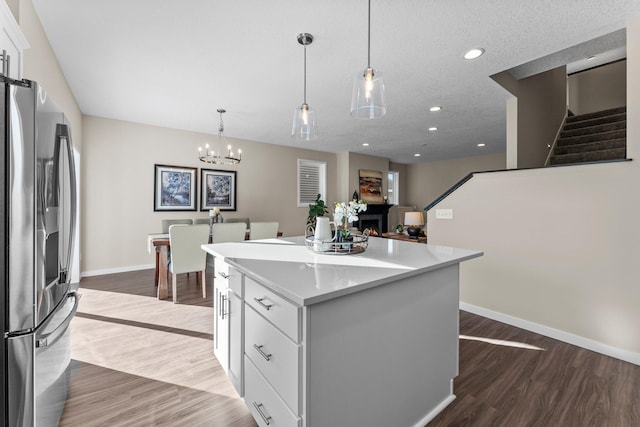 kitchen featuring stainless steel fridge with ice dispenser, hanging light fixtures, a center island, and white cabinets