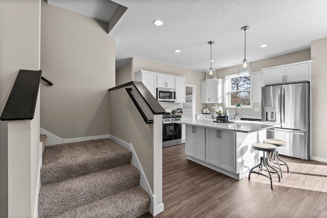 kitchen featuring white cabinetry, decorative light fixtures, a kitchen island, and appliances with stainless steel finishes