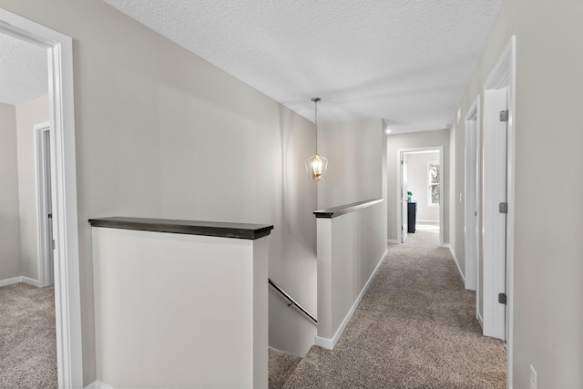 corridor featuring light carpet and a textured ceiling