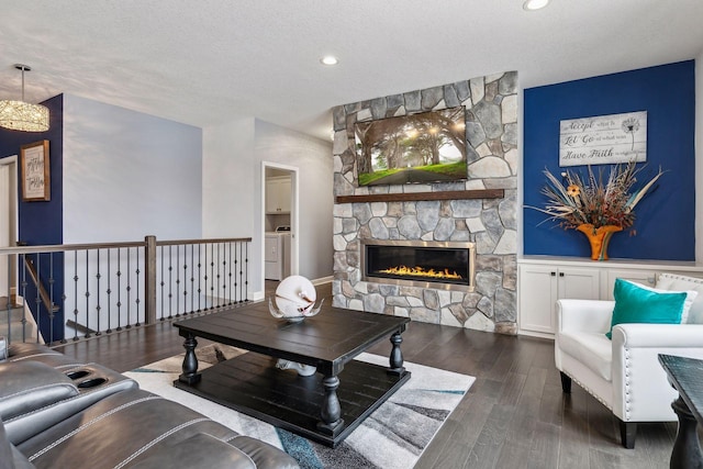 living room featuring a fireplace, dark wood-type flooring, washer and dryer, and a textured ceiling