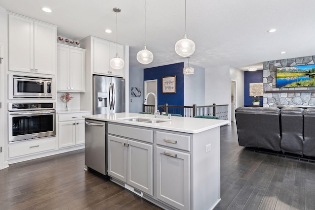 kitchen with decorative light fixtures, an island with sink, white cabinetry, sink, and stainless steel appliances