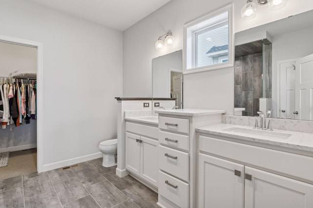 bathroom with walk in shower, vanity, and toilet