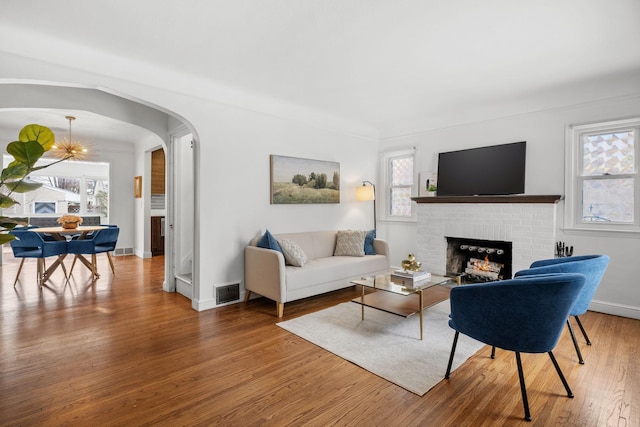 living room featuring wood-type flooring, a chandelier, and a fireplace