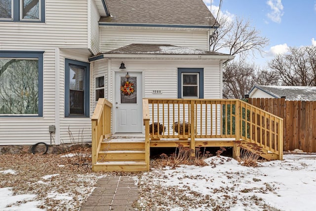 snow covered property entrance with a deck