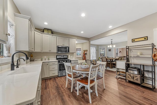 kitchen with pendant lighting, dark hardwood / wood-style flooring, stainless steel appliances, an inviting chandelier, and sink