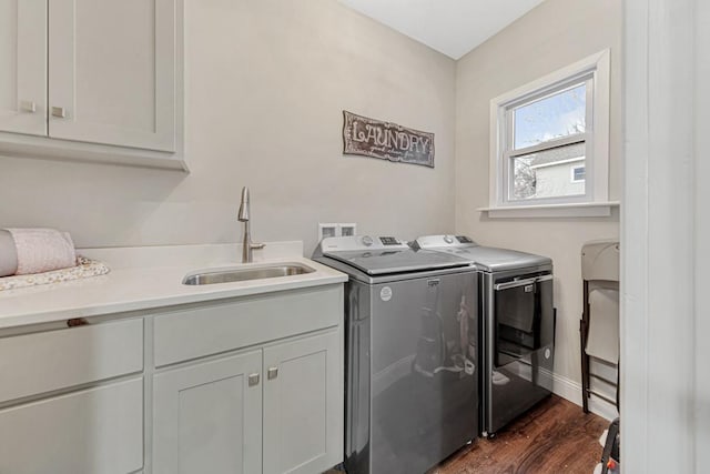 clothes washing area featuring cabinets, sink, dark hardwood / wood-style flooring, and washing machine and clothes dryer