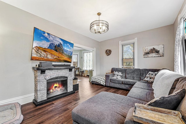 living room with dark wood-type flooring, a chandelier, and a fireplace