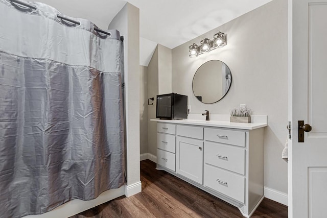 bathroom with wood-type flooring, vanity, and shower / tub combo with curtain