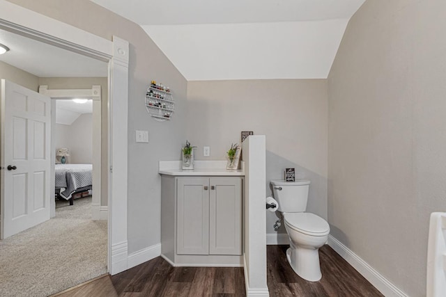 bathroom featuring toilet, lofted ceiling, hardwood / wood-style floors, and vanity