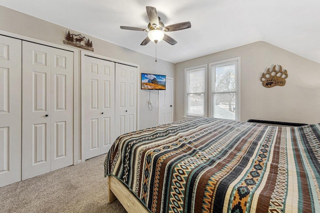 carpeted bedroom featuring ceiling fan, vaulted ceiling, and multiple closets