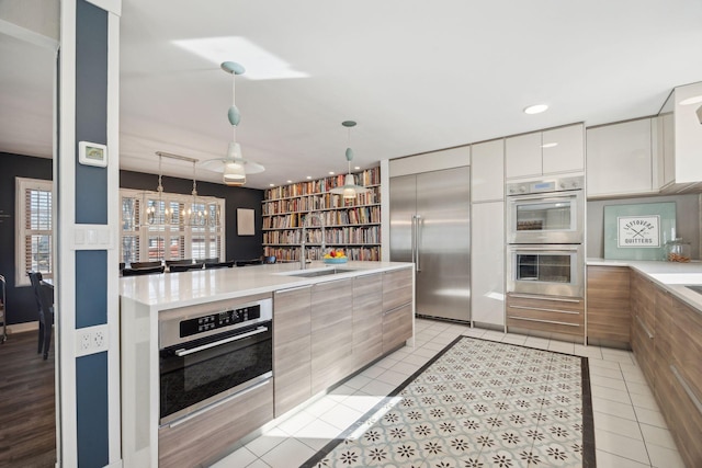 kitchen with sink, white cabinets, hanging light fixtures, light tile patterned floors, and stainless steel appliances