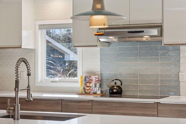 kitchen with white cabinetry, sink, black electric stovetop, and backsplash