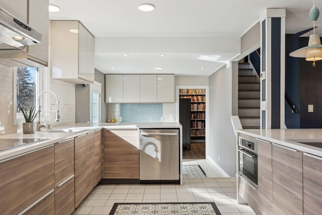 kitchen with sink, tasteful backsplash, white cabinetry, light tile patterned floors, and appliances with stainless steel finishes