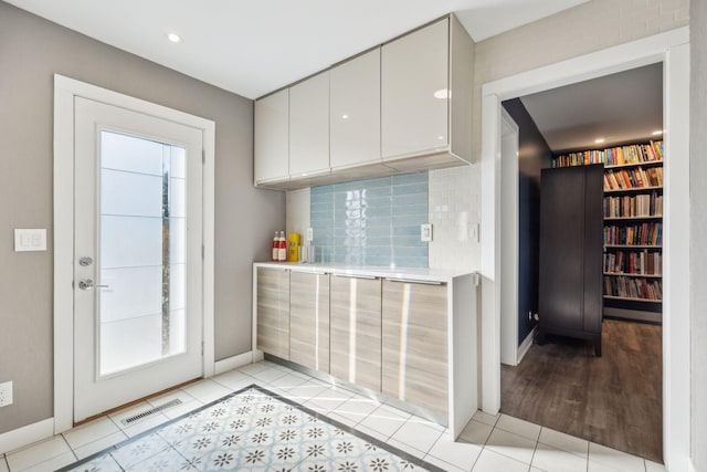 kitchen with tasteful backsplash, plenty of natural light, light tile patterned floors, and white cabinets