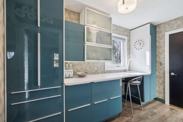 kitchen with blue cabinets, tasteful backsplash, hardwood / wood-style floors, and paneled built in fridge