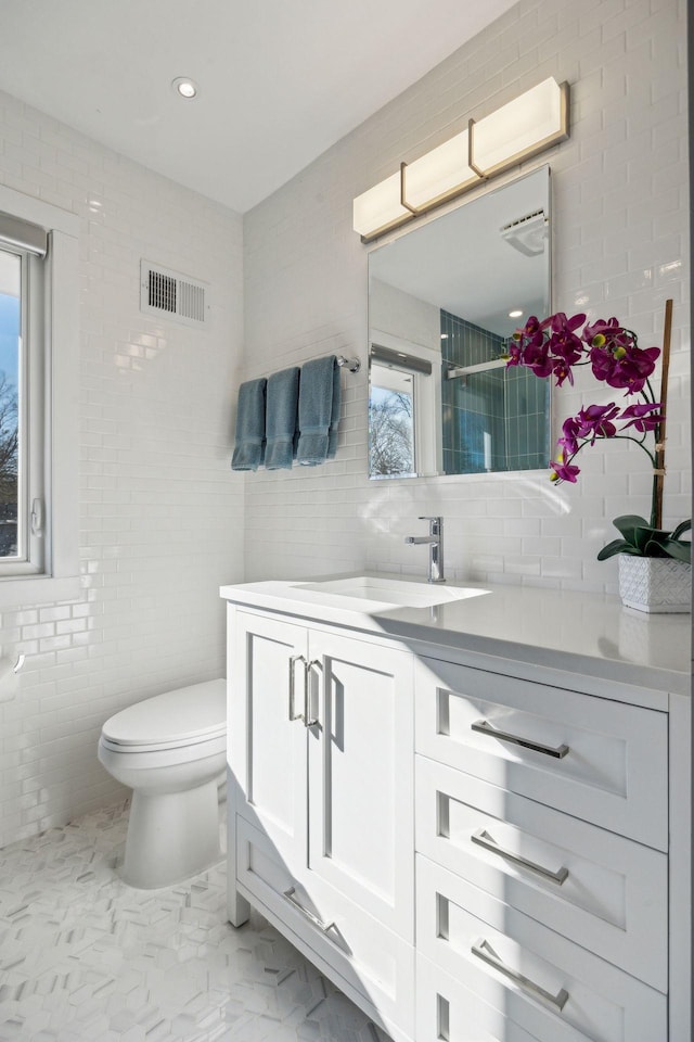 bathroom featuring tile walls, vanity, and toilet