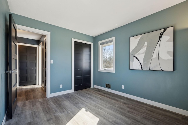 unfurnished bedroom featuring dark hardwood / wood-style flooring and a closet