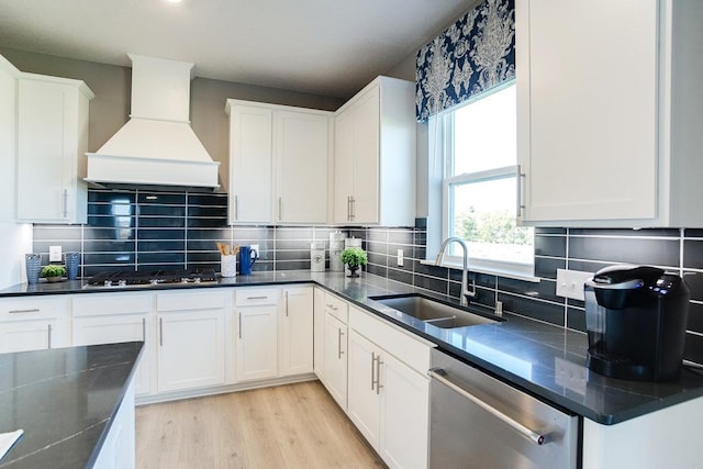 kitchen featuring sink, stainless steel appliances, premium range hood, white cabinets, and light wood-type flooring