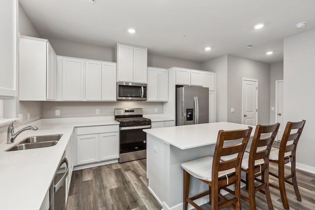 kitchen with sink, appliances with stainless steel finishes, dark hardwood / wood-style floors, a center island, and white cabinets