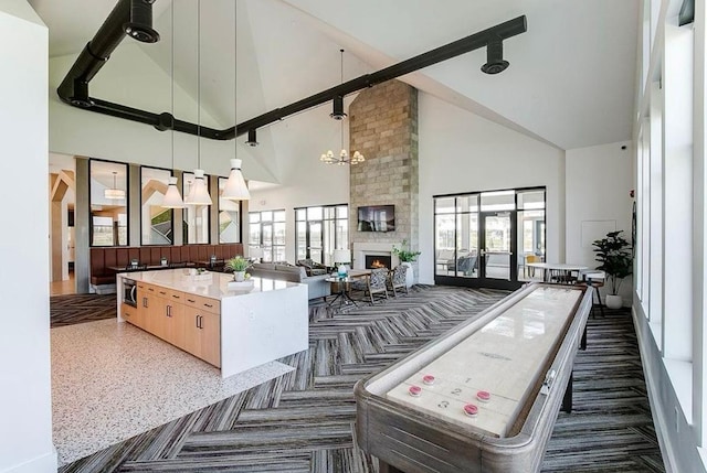 game room with a large fireplace, french doors, high vaulted ceiling, and an inviting chandelier