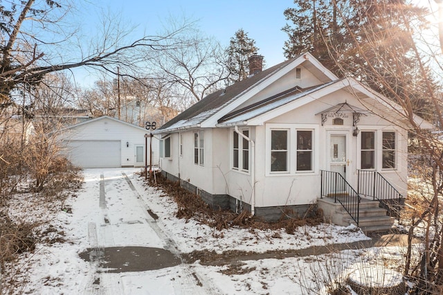 bungalow with a garage and an outbuilding