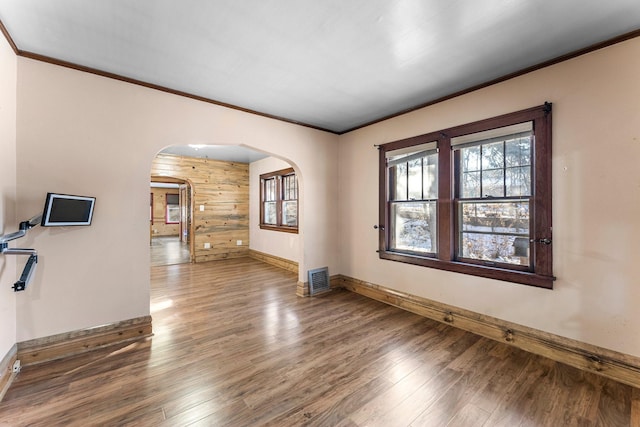 unfurnished living room featuring wood-type flooring and ornamental molding