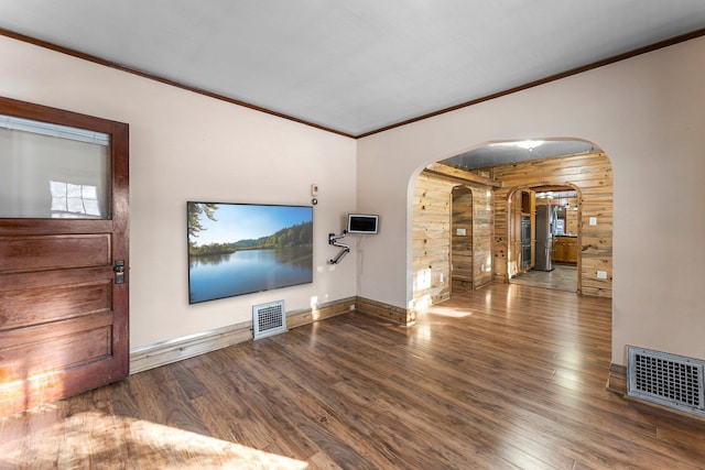 unfurnished living room featuring wooden walls, dark hardwood / wood-style floors, and ornamental molding