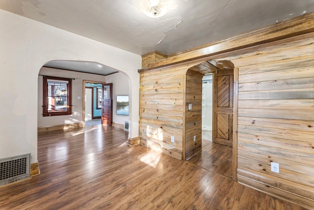 empty room with wood walls and dark wood-type flooring